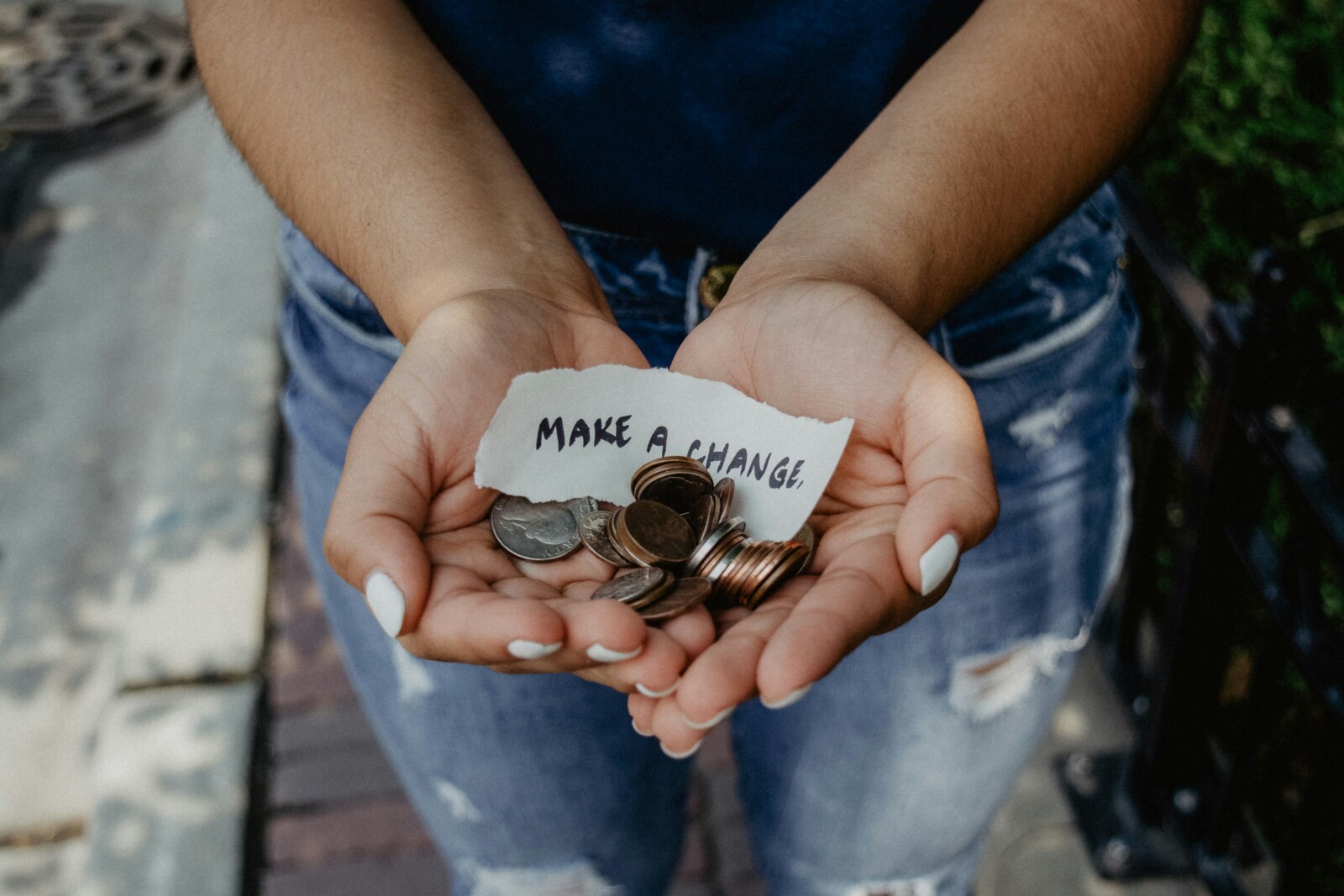 Person showing both hands with a "Make a Change" note and coins