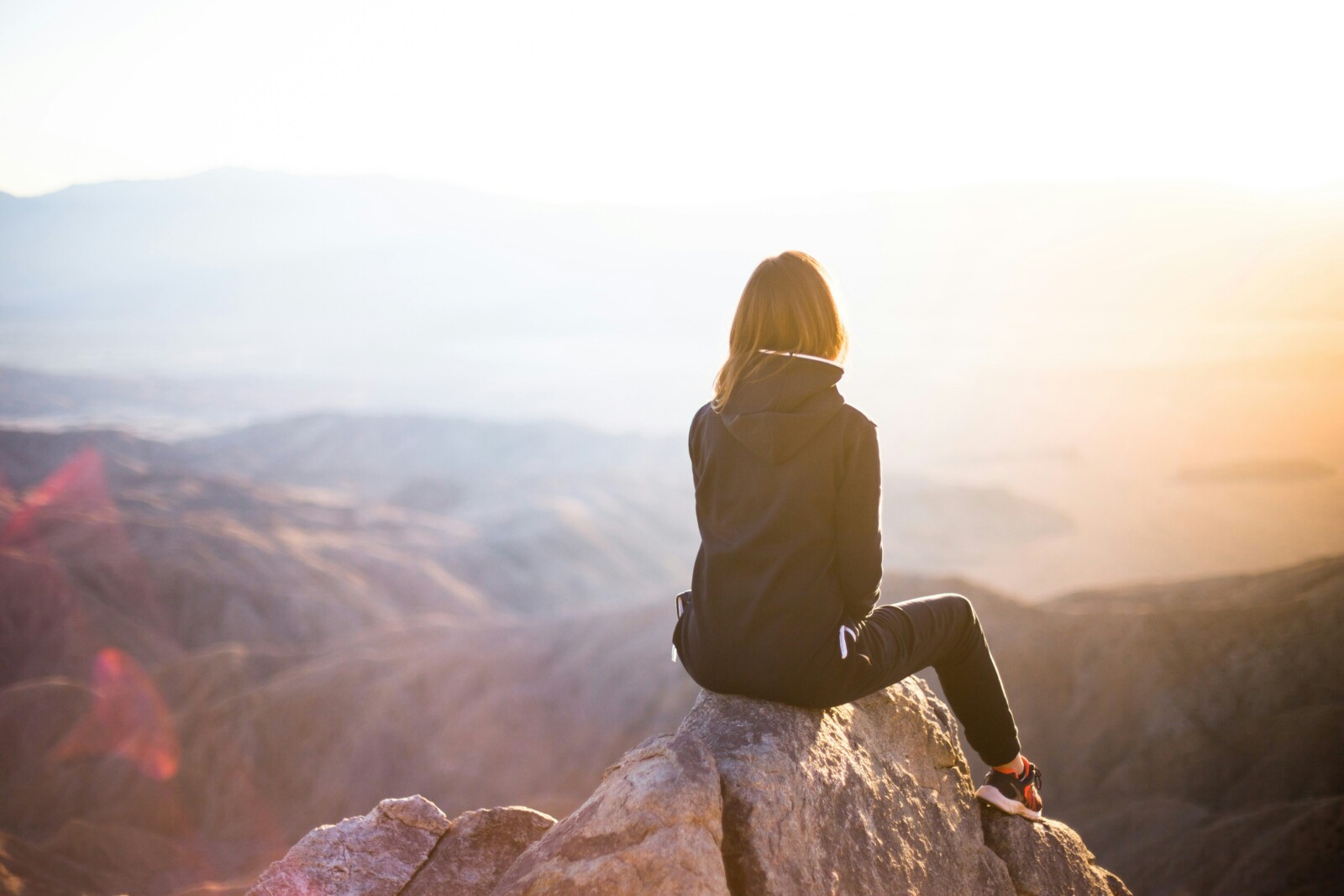 Pensive woman watching a sunset on a mountain peak.